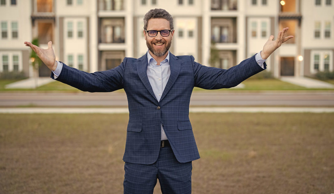 Ein Verwalter in witziger Pose vor einem Mehrfamilienhaus