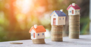 Häuser die sich auf gestapeltem Geld befinden